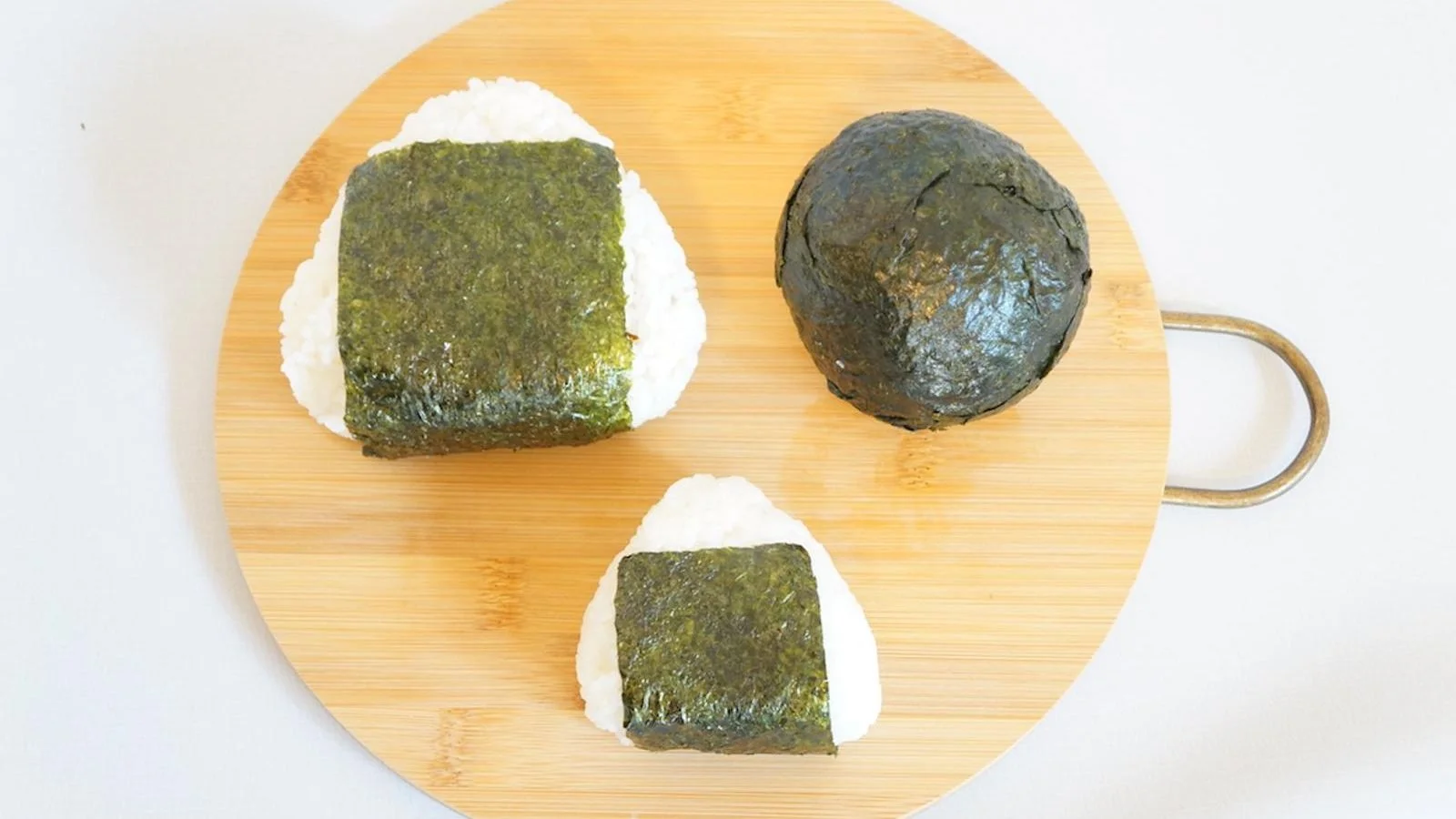 A bakudan on a board beside a large triangle onigiri and a small one