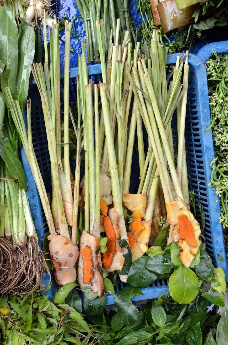 Lemongrass stalks bundled with galangal and kaffir lime leaves at a market